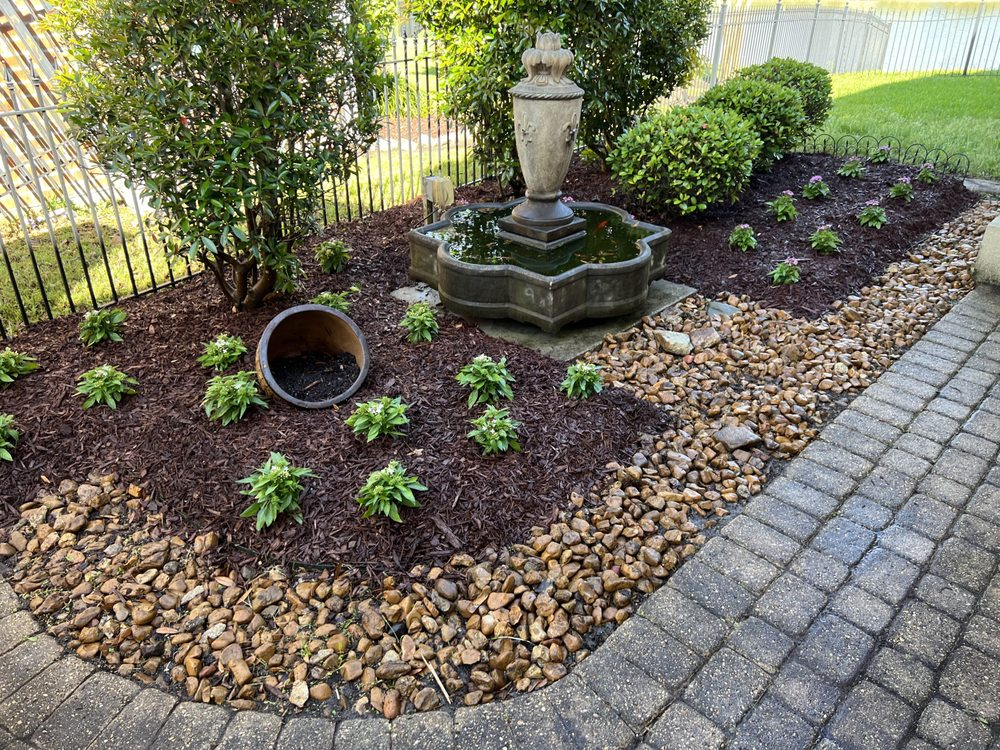 Planted garden bed with a fountain, fresh mulch and decorative stone edging